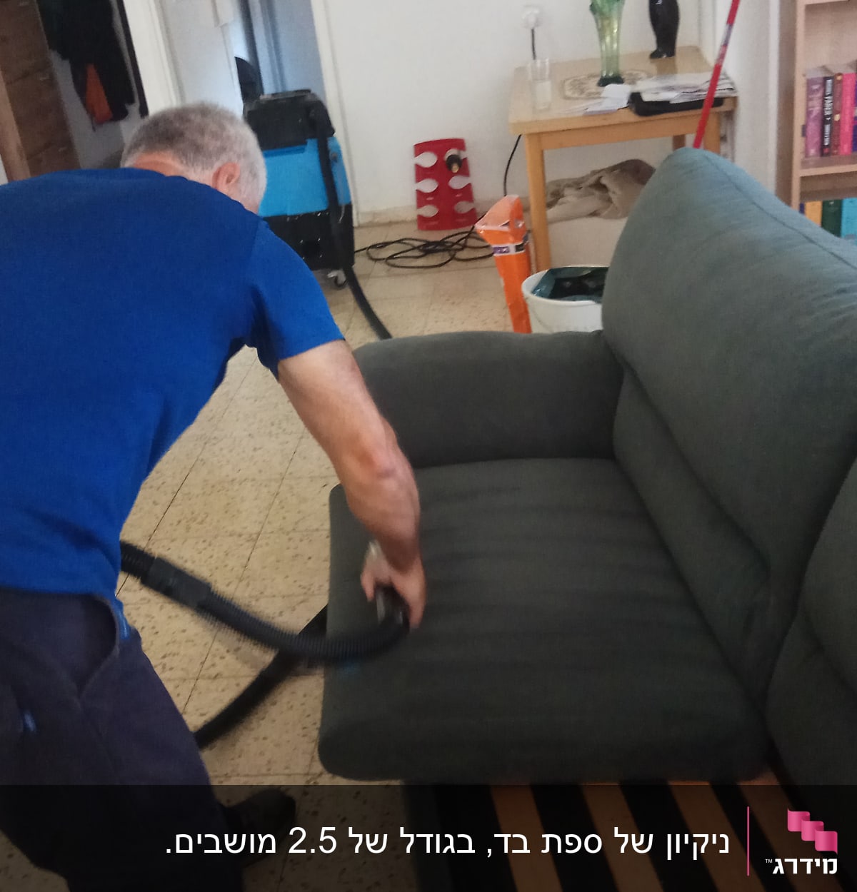 אדם מנקה ספה עם שואב אבק